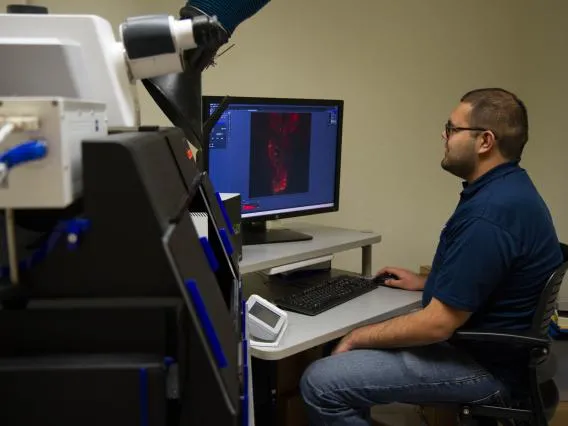 a man wearing glasses sits in front of a computer editing an abstract image