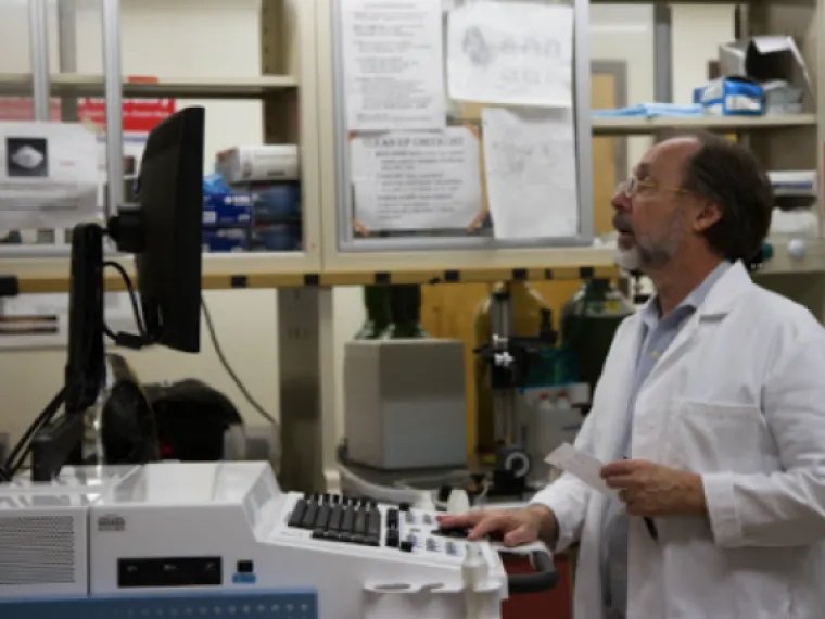 a man in a labcoat stands in front of a monitor